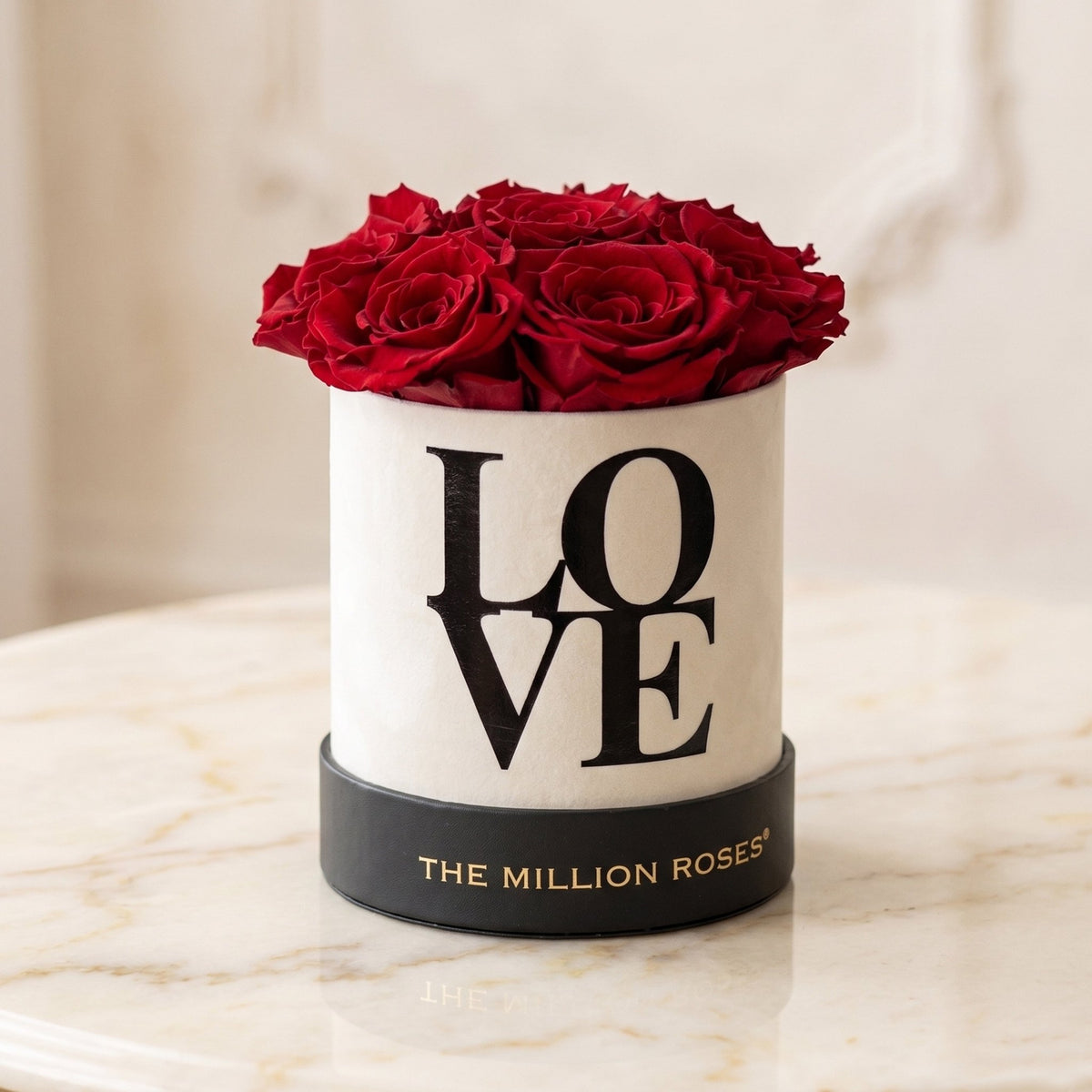 Luxurious white box with preserved red roses and 'LOVE' text on a marble surface, featuring 'The Million Roses' brand.