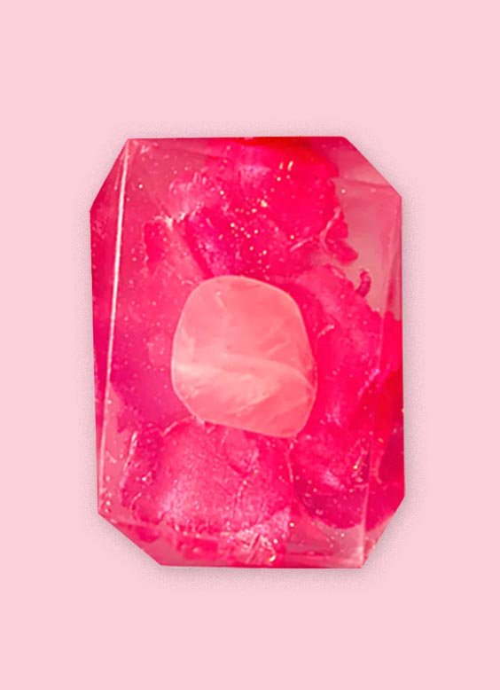 Pink crystal shaped cleansing soap bar with flower petal floral design on a pink background